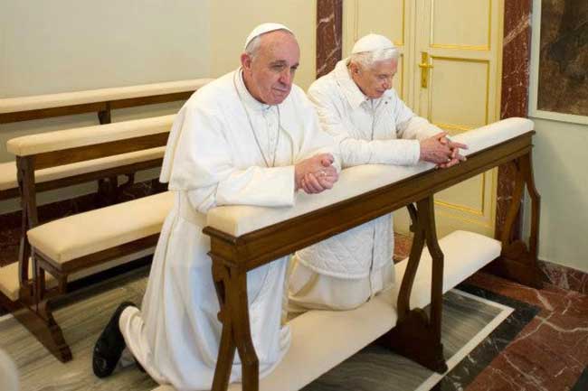 Papas Francisco e Bento XVI rezando de joelhos